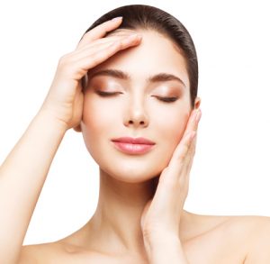 Beautiful woman with clean, clear skin feeling face, eyes closed